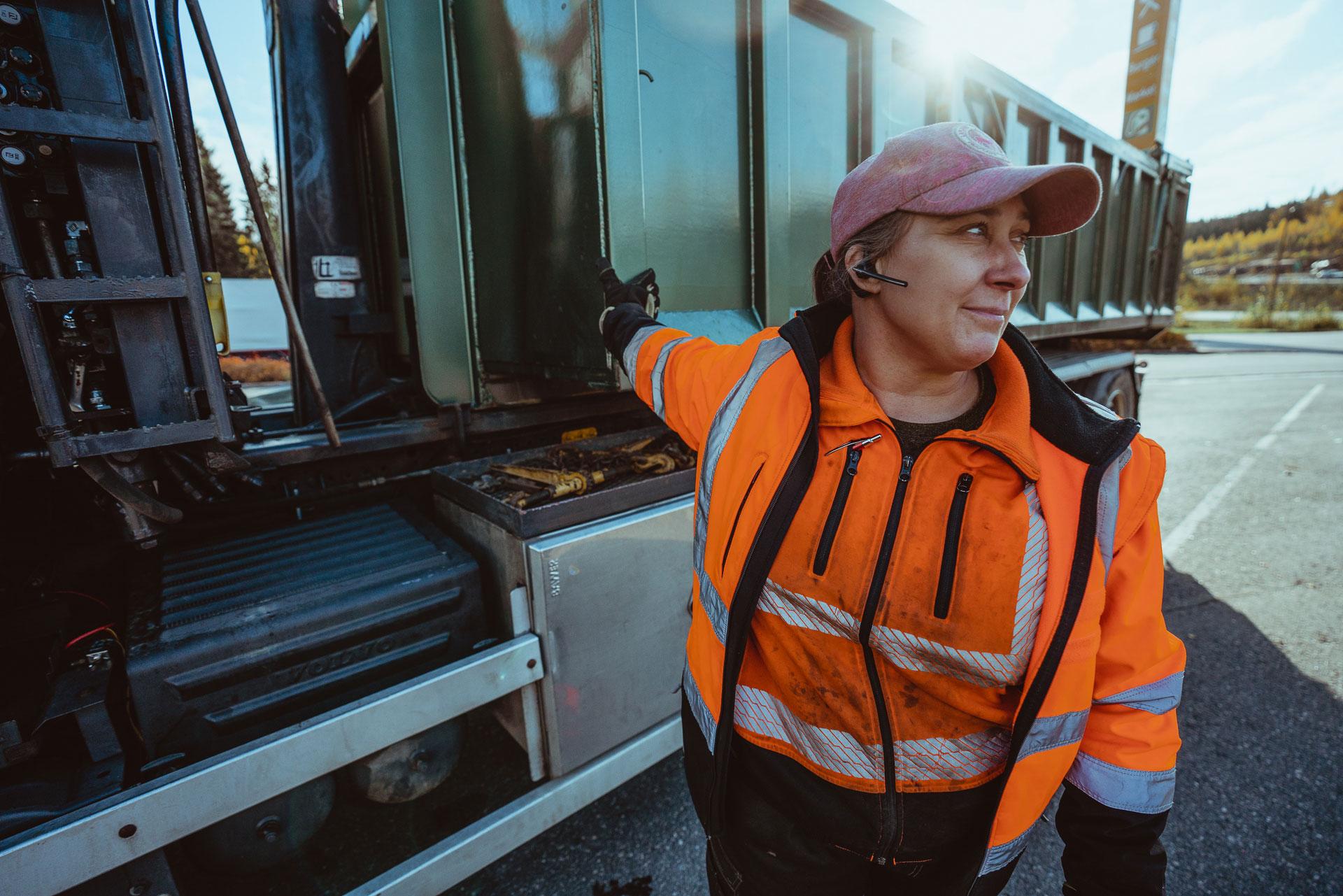 A woman stretches her arm against the side of a truck.